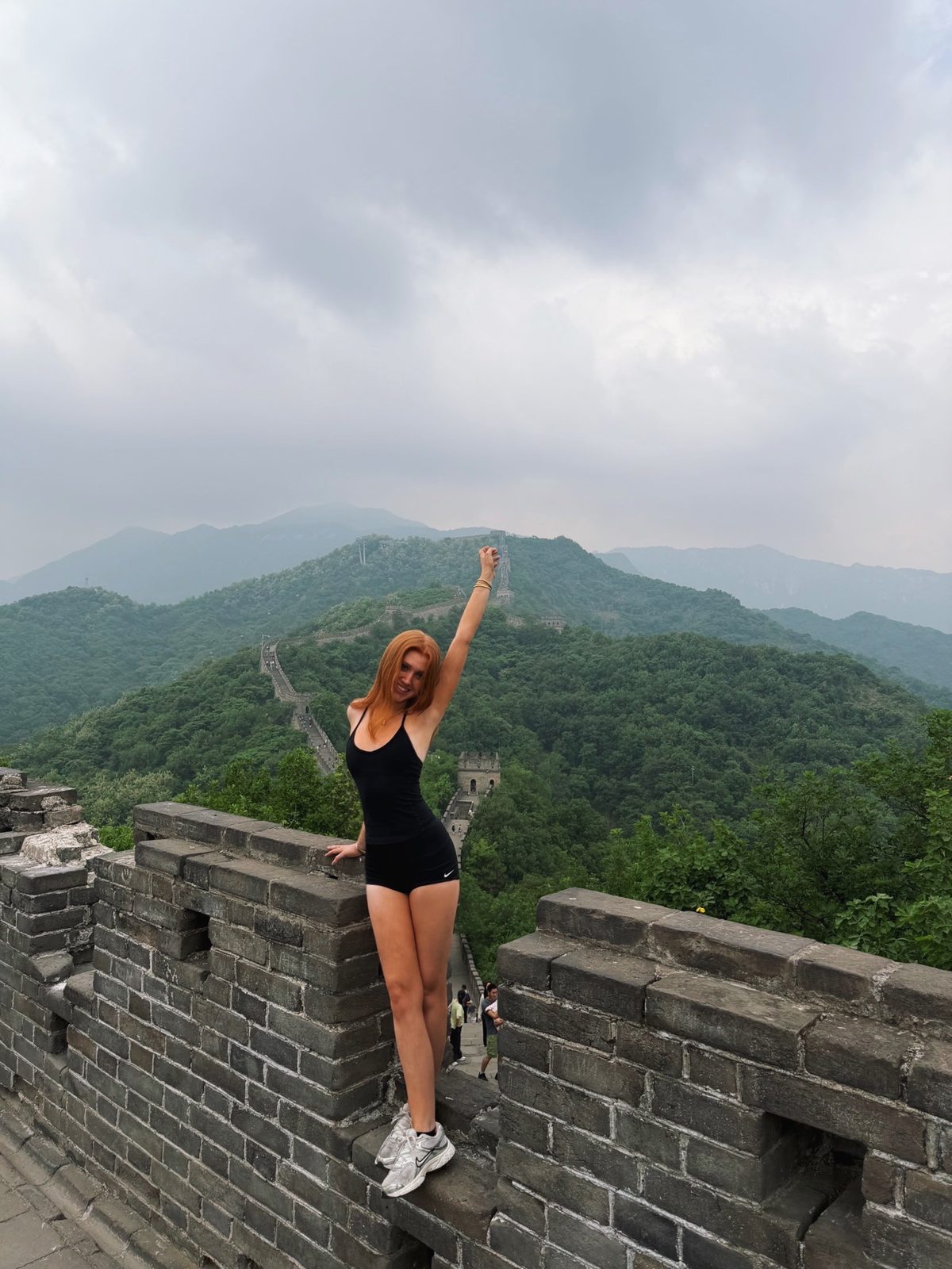 Delaney on the Great Wall with green mountains behind her